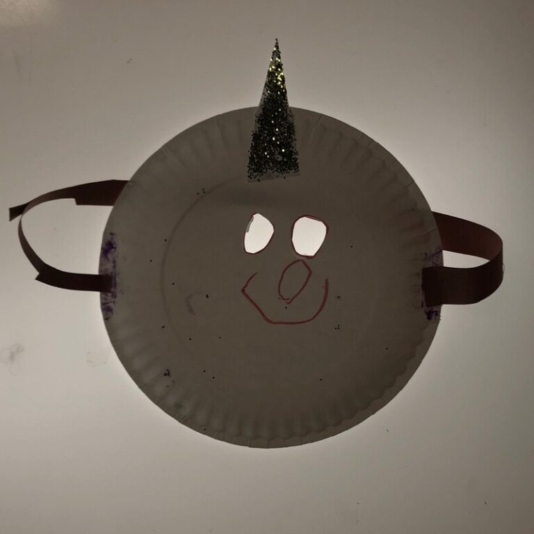 A unicorn mask made from a paper plate, complete with a glittery horn.